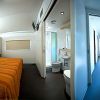 Interno modern con camera da letto dai colori caldi, bagno compatto e corridoio luminoso.
