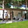 Una veranda con sedie e tavolo all'aperto, persone sedute sotto gli alberi.