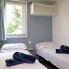 Stanza con due letti singoli, finestra, e asciugamani blu su ciascun letto.