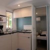 Cucina compatta con piano cottura, microonde, caffettiera e vista su una camera da letto.