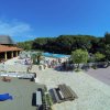 Area con piscina, parco giochi, e tavoli all'aperto, circondata da vegetazione.