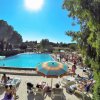 Piscina soleggiata con lettini e ombrelloni colorati.