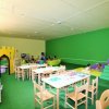 Sala giochi per bambini con tavoli e giochi colorati.
