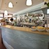 Un bar elegante con bancone chiaro, bottiglie sullo scaffale e ciotole di snack sulla superficie.