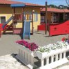 Un'area giochi per bambini con scivolo blu e strutture colorate, circondata da fiori.