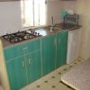 Cucina con mobili blu, lavandino, fornelli a gas e mini frigo.