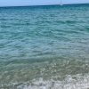 Acqua cristallina di mare con piccole onde, barca all'orizzonte.
