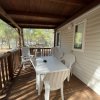 Veranda in legno con tavolo bianco e sedie di plastica.