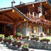 Chalet rustico con balcone fiorito e tetto in legno, immerso nella natura.