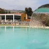 Piscina con cascata e lettini in lontananza.
