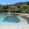Piscina con acqua limpida e vegetazione attorno.