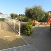 Passerella esterna con parco giochi e alberi.