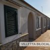 Villetta con persiane verdi e portico.