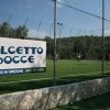 Campo da calcetto all'aperto con cartello e rete di recinzione.