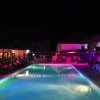 Piscina illuminata di notte con luci rosa intorno.