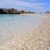 Spiaggia con ciottoli e mare limpido.