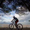 Uomo in bicicletta lungo una spiaggia.