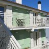 Edificio verde con balcone e scale esterne.