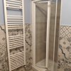 Cabina doccia e termosifone in bagno piastrellato.