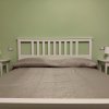 Camera da letto con letto matrimoniale e comodini bianchi.