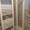 Doccia e scaldasalviette in bagno con piastrelle decorate.
