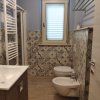 Bagno con piastrelle decorate, lavabo, bidet e finestra.