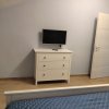 Camera con letto blu, cassettiera bianca e TV.