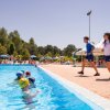 Istruttori camminano vicino a piscina con nuotatori.