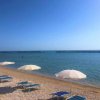 Spiaggia di ghiaia con ombrelloni e mare calmo.