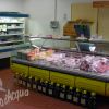 Banchi refrigerati con carne e formaggi in un negozio.