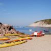 Kayak e pedalò colorati su una spiaggia sabbiosa.
