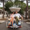 Famiglia su un golf cart tra villette bianche e alberi.
