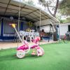 Tenda con triciclo rosa davanti; bici accanto all'ingresso.