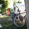 Camper e biciclette in campeggio, alberi e tende accanto.