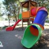Un parco giochi con scivoli colorati sotto gli alberi.