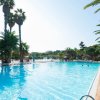 Piscina all'aperto con lettini e palme.