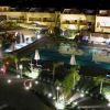 Vista notturna di una piscina con ombrelloni e giardino illuminato.