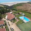 Vista aerea di un complesso turistico con piscina, campi sportivi e mare sullo sfondo.