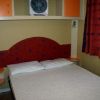 Camera con letto matrimoniale, testiera rossa decorata e armadi arancioni.