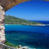 Vista sul mare attraverso un arco in pietra.