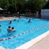 Piscina esterna con persone che nuotano e si rilassano al sole.