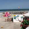 Spiaggia con molte sdraio, un gonfiabile rosa e vista sull'oceano.