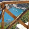 Staccionata di legno con vista su barche in una baia turchese.