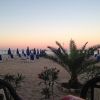 Spiaggia al tramonto con ombrelloni blu.
