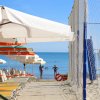 Una spiaggia con sedie a sdraio, ombrelloni e vista sul mare.