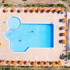Piscina con ombrelloni arancioni vista dall'alto.