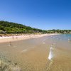 Spiaggia sabbiosa con bagnanti e ombrelloni gialli e arancioni.