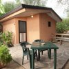 Un bungalow con patio, tavolo e sedie in un giardino.