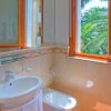 Bagno con lavabo, bidet e finestra su palme.