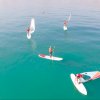 Persone praticano paddleboarding in mare calmo.